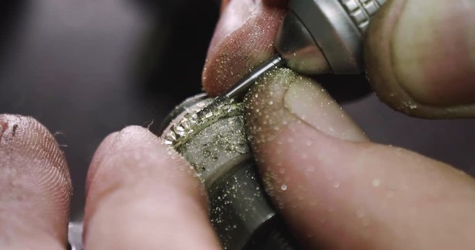 Close up of the hands of a goldsmith while he is working on a diamond ring.