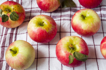 Fresh red apples with green leaves on a napkin. Dark wooden background.