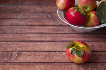 Fresh red apples with green leaves on a Dark wooden background.