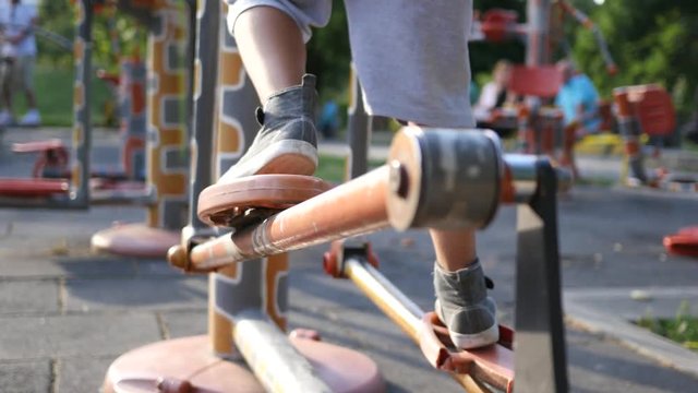 Fitness training ground in the park - kid boy legs twist the bicycle pedals