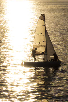 VELERO AL ATARDECER FORMANDO UNA SILUETA CON UNA LUZ DORADA QUE TRANSMITE TRANQUILIDAD 
