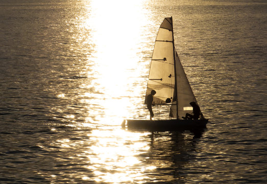 VELERO AL ATARDECER FORMANDO UNA SILUETA CON UNA LUZ DORADA QUE TRANSMITE TRANQUILIDAD 