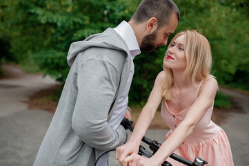 Talking couple near the modern bicycle in park. Love and tenderness, dating, romance. Lifestyle concept. Family vacations and relax feelings