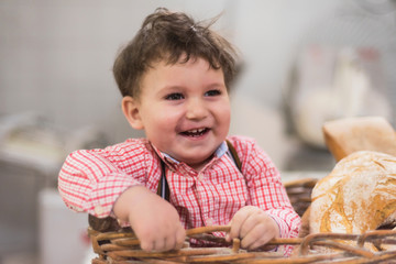 Portrait of a cute baby inside a basket with bread in the bakery