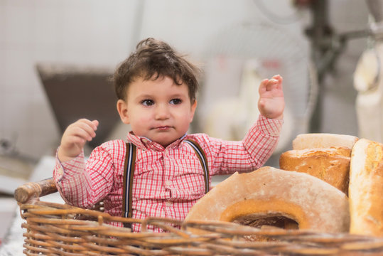 Portrait of a cute baby inside a basket with bread in the bakery