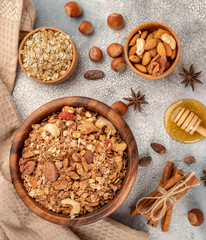 Homemade granola in wooden bowl with ingredients - oat, nuts, honey and spice cinnamon and anise