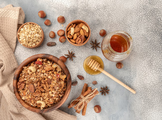 Homemade granola in wooden bowl with ingredients - oat, nuts, honey and spice cinnamon and anise