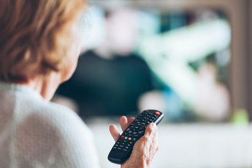 Senior woman with remote control watching tv