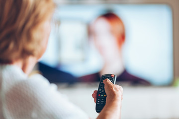 Senior woman with remote control watching tv