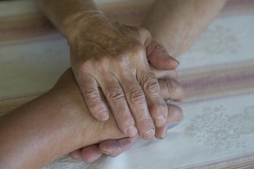 Hands of an elderly woman holding the hand of a younger woman. Lots of texture and character in the old ladies hands.