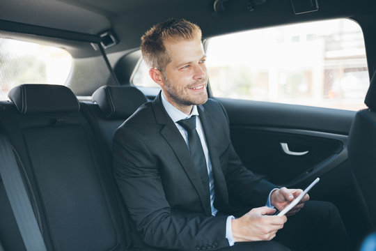 Executive businessman at the back of car using a digital tablet