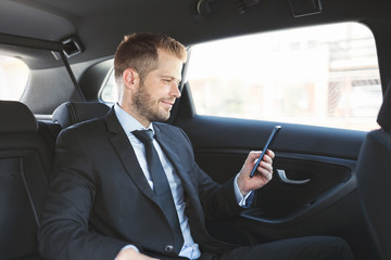 Fototapeta na wymiar Executive businessman at the back of car using a mobile phone