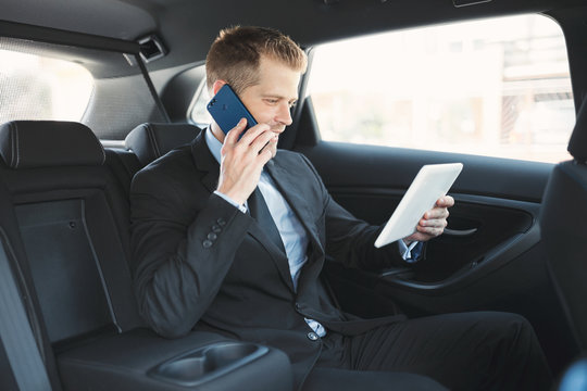 Executive Businessman At The Back Of Car Using A Mobile Phone