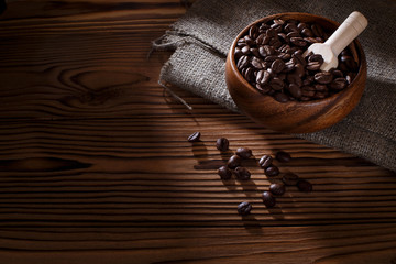 Roasted coffee beans in a wooden bowl on dark background