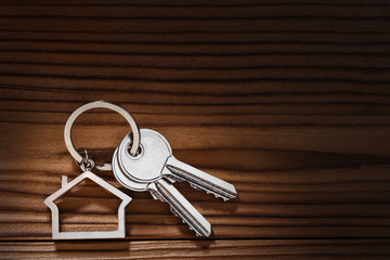 House keys with house shaped keychain on dark wooden background