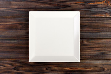 Empty square White Plate on Wooden Table Top View