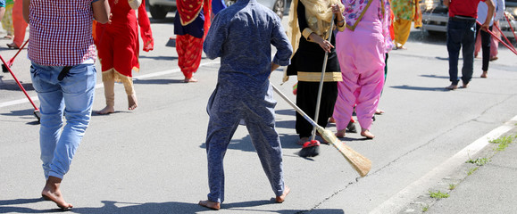 barefoot Sikh dressed in traditional clothes clean the street