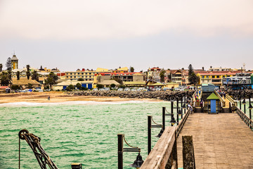 Long pier, walking people, residential houses on coastline of Swakopmund German colonial town,...