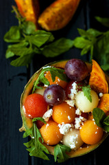 Fruit salad in melon with mint, tasty summer dessert. Black background