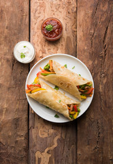 Indian Veg chapati Wrap / Kathi Roll, served in a plate with sauce over moody background. selective focus