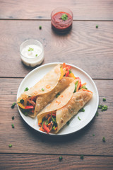 Indian Veg chapati Wrap / Kathi Roll, served in a plate with sauce over moody background. selective focus