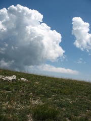 Very bright white clouds on top of a mountain with a dark blue sky