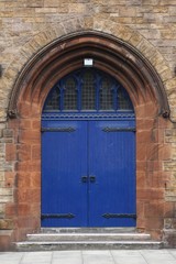 Fototapeta na wymiar Painted blue arched door set in an ancient stone wall