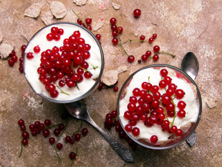 Healthy dessert with organic red currants, fresh yogurt and corn flakes. Dietary breakfast on a brown background