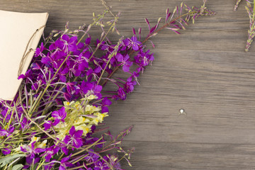 Willow-herb purple flowers on old grunge wooden background. Top view. Minimalistic mockup.