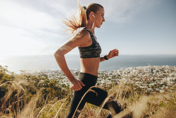 Woman training for marathon on mountain trail.