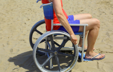 man with wheelchair on the beach in summer