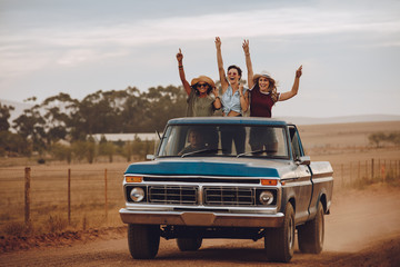 Excited friends traveling by a pickup truck © Jacob Lund