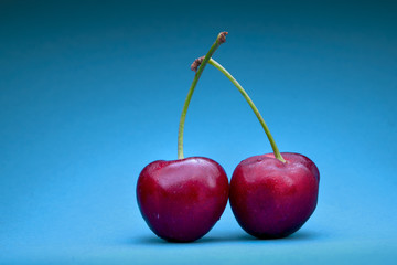 two cherries in front of blue background