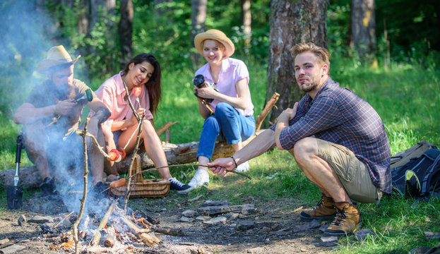 Company having hike picnic nature background. Hikers sharing impression of walk and eating. Summer hike. Picnic with friends in forest near bonfire. Tourists with camera relaxing checking photos
