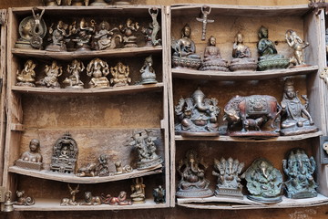 Many old statuettes on wooden shelves