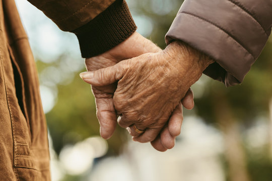 Elderly couple holding hands and walking