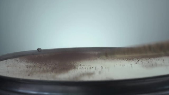 Brown holi powder bounces off drum in shockwave pattern.