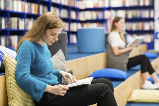 Teenage girls sitting in a public library reading book