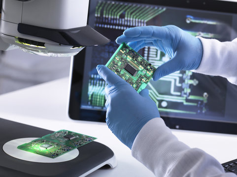 Engineer using a d stereo microscope for quality control in the manufacturing of circuit boards for the electronics industry