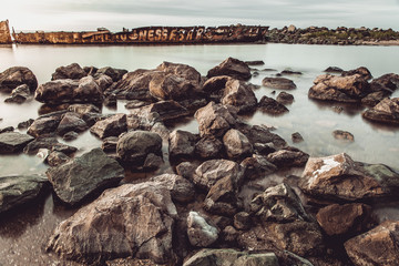 The wild sea beach with stones at sunrise. Big stones on the beach. Morning inflow of water. Nessebar. Bulgaria
