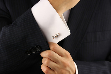 Elegant young fashion man fixing a gold cufflinks