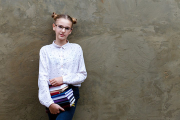 High school, university serious young girl holding books. Gray concrete wall background. Education and school concept