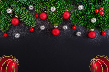 christmas black background with fir tree branch and decoration, red berrys and baubles, copy space
