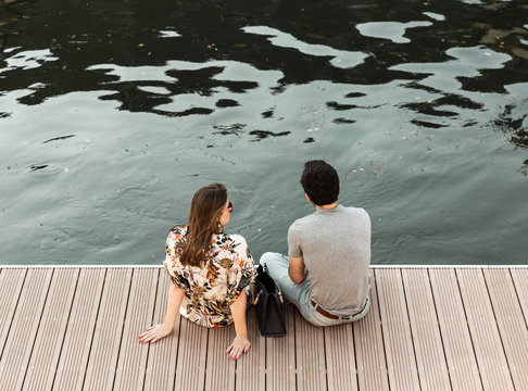 Couple assis au bord d'un quai en ville