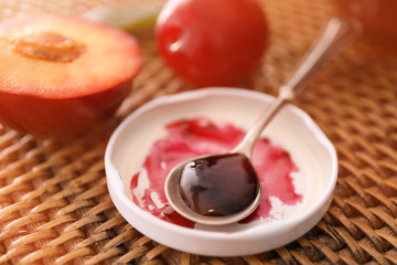 Spoon with tasty plum jam on table