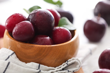 Bowl with ripe juicy plums on table