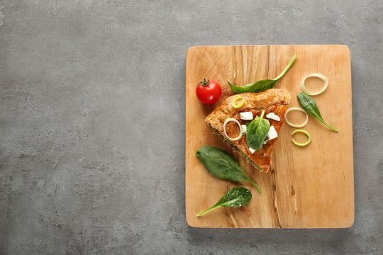 Piece of tasty pie with spinach on wooden board