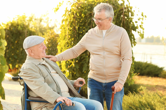 Senior man in wheelchair with his friend from care home outdoors