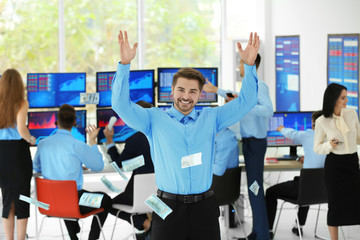 Happy male stock trader throwing dollar bills in office