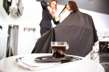Tray with cup of coffee on table in beauty salon